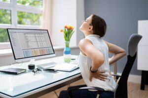 Woman_with_painful_back_while_sitting_at_a_desk.